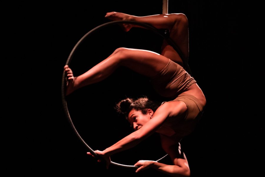 A peron twisted around a hoop suspended in the air.